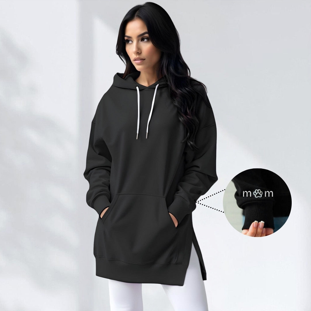 Woman wearing a black hoodie dress with an embroidered dog mom heart on the sleeve, standing and facing forward to show the fit and style.